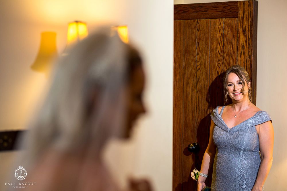 A woman in a blue lace dress stands in a doorway with warm lighting.