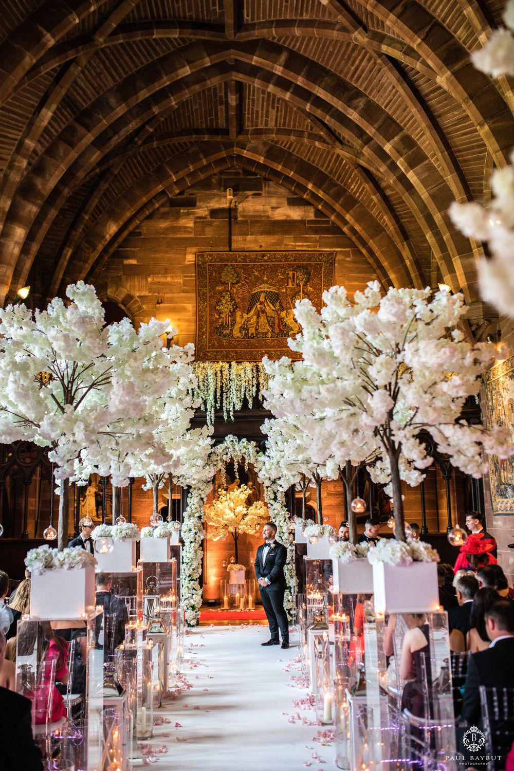 Elegant church wedding ceremony setup with white cherry blossom trees lining the aisle and arched ceiling.