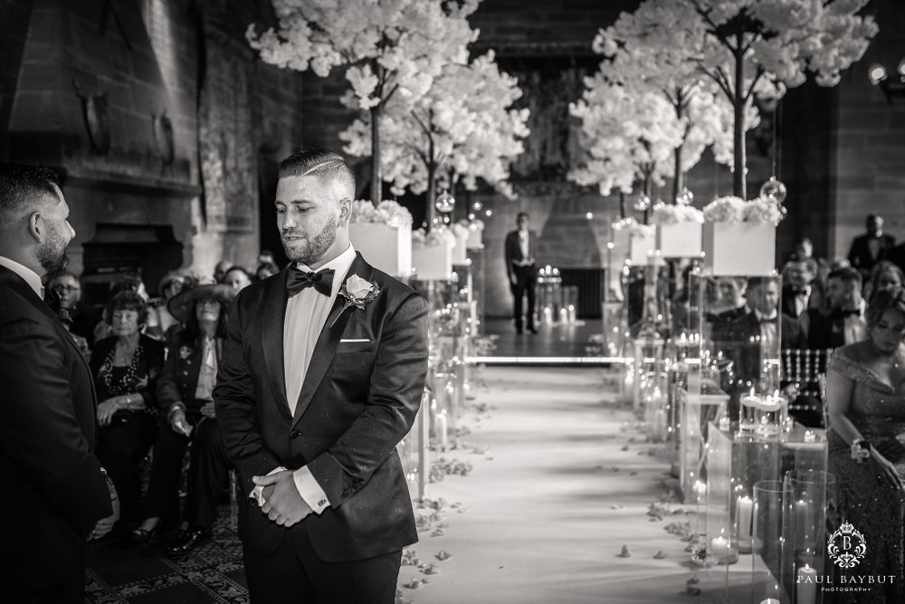 Black and white photo of wedding ceremony in grand cathedral with white floral decorations.