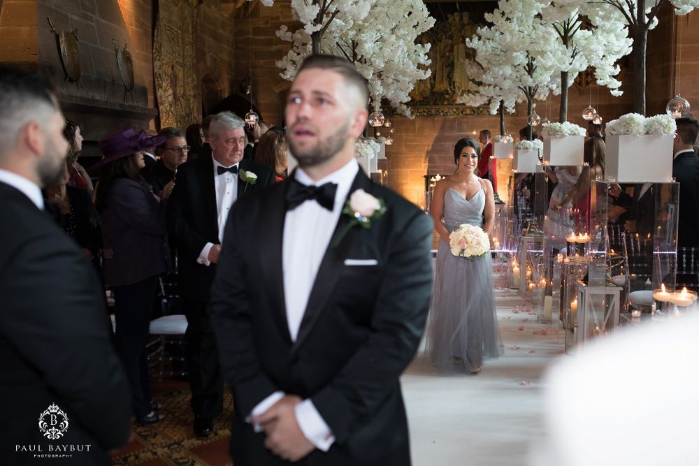 Wedding ceremony in stone church with white cherry blossom trees and glowing candlelight.