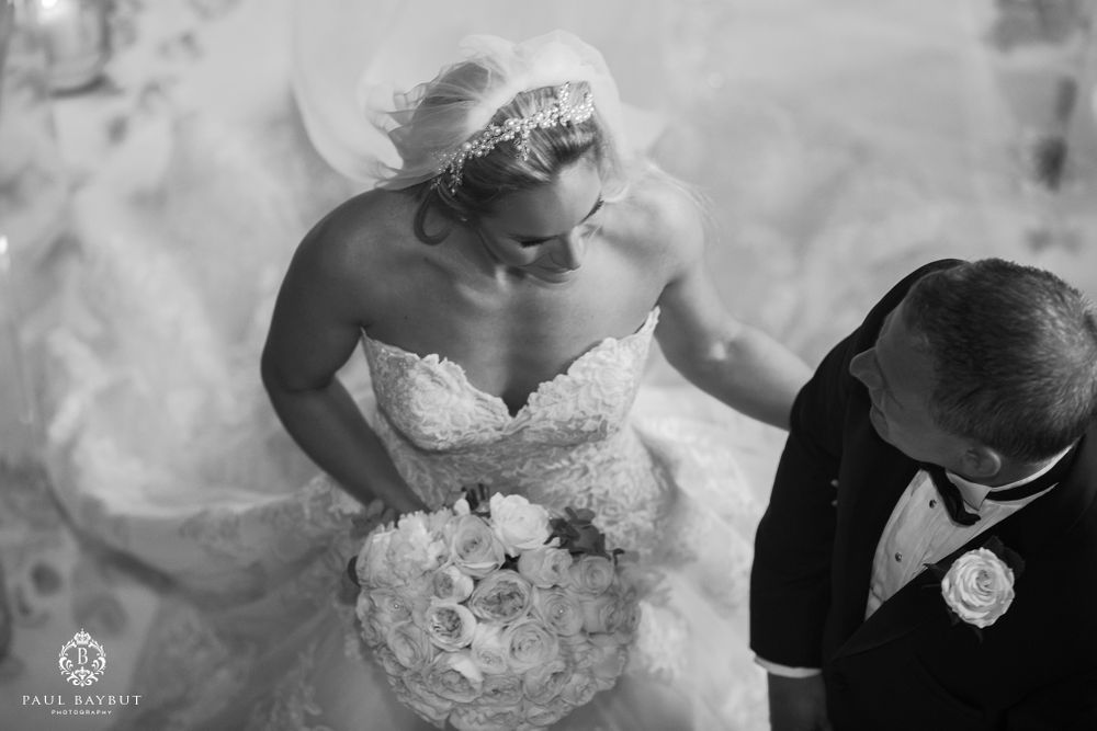 Black and white wedding photo showing couple with white floral bouquet during ceremony.