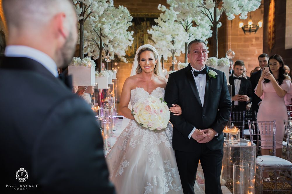Wedding celebration with white floral arrangements and chandelier lighting in luxurious venue.