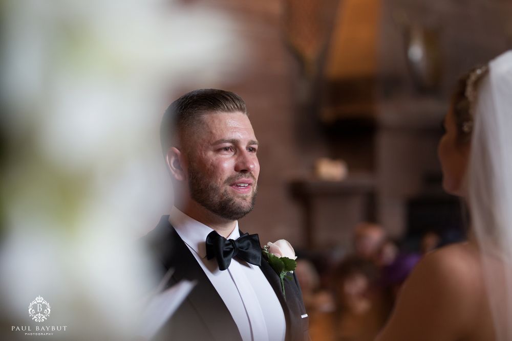 Side profile portrait of groom in tuxedo with boutonniere during wedding ceremony.