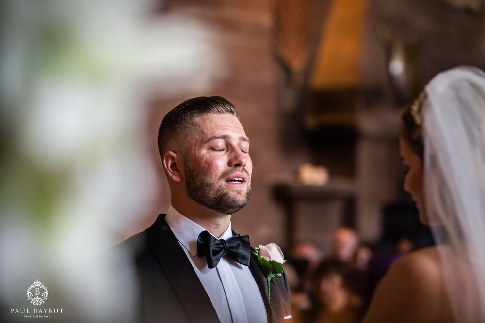 An emotional moment captured during wedding vows in an ornate indoor ceremony venue.
