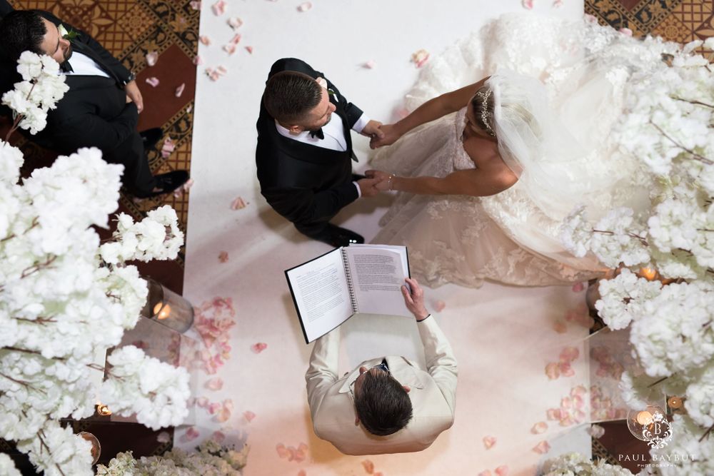 Overhead view of wedding ceremony with couple sitting surrounded by white floral petals.