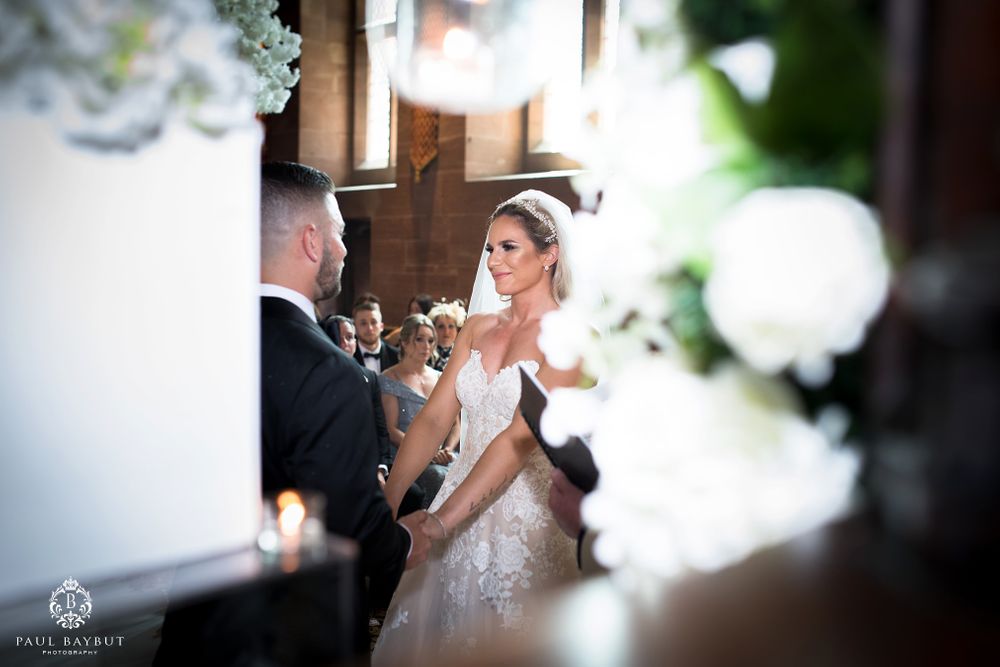 An intimate moment during a wedding ceremony surrounded by white floral arrangements and soft lighting.