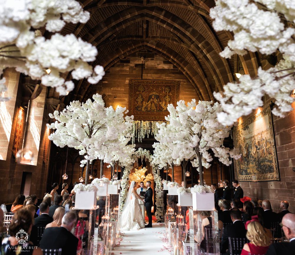 A cathedral wedding ceremony with stunning white floral decorations hanging from an arched ceiling.