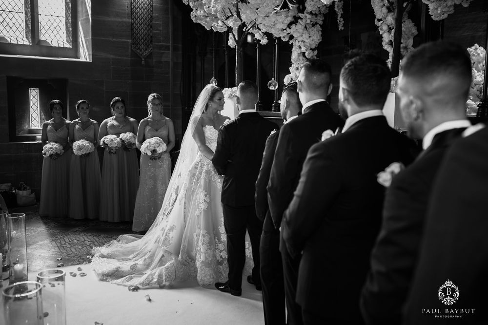 Black and white photo of a wedding ceremony in a traditional church setting with elegant decor.