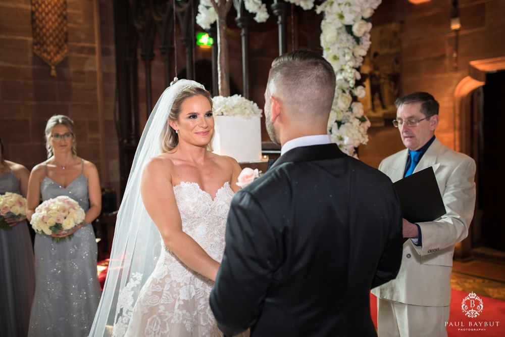 A wedding ceremony unfolds in a beautiful church setting with white floral arrangements.