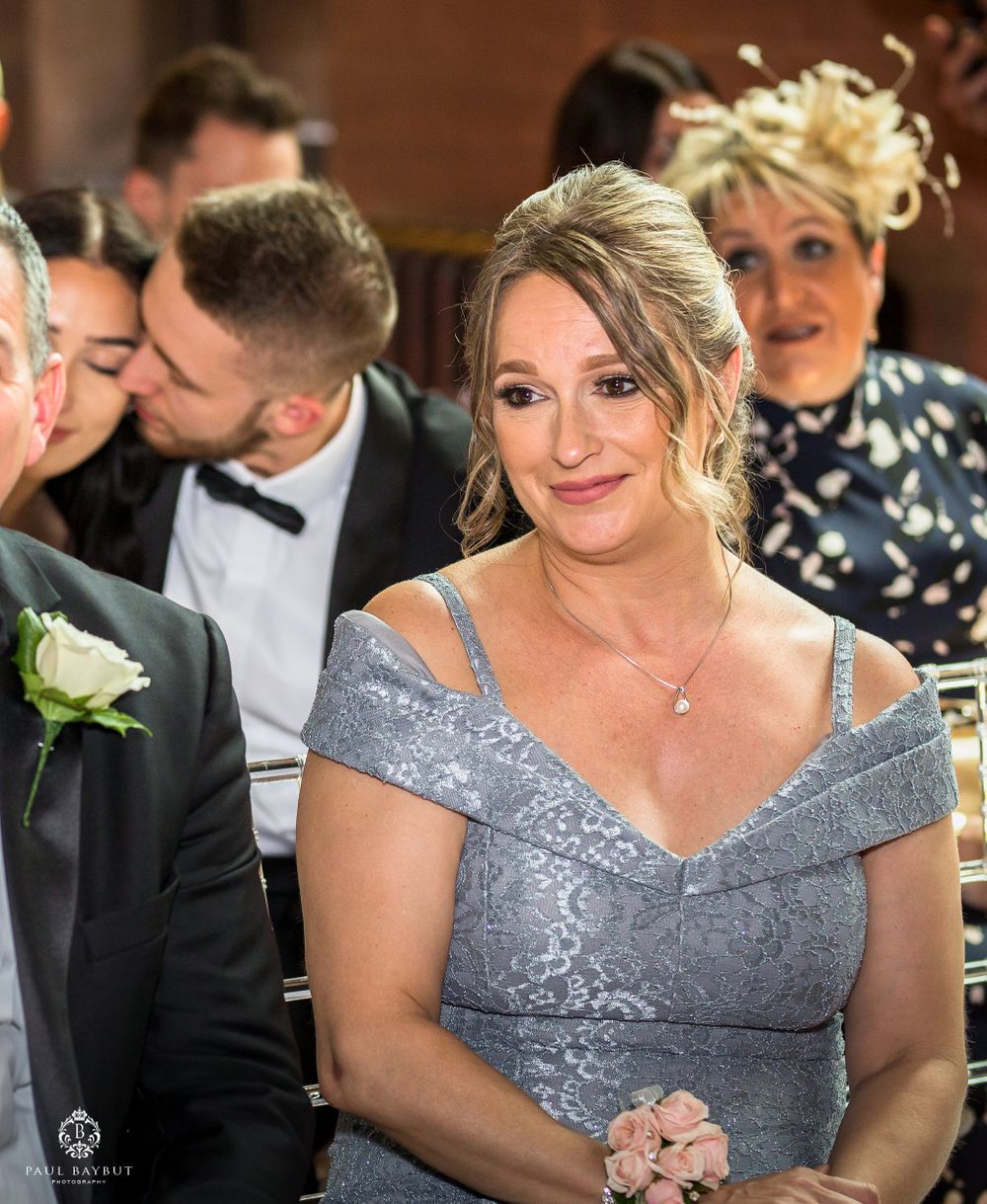 Wedding guest in grey lace dress smiles during reception dinner.
