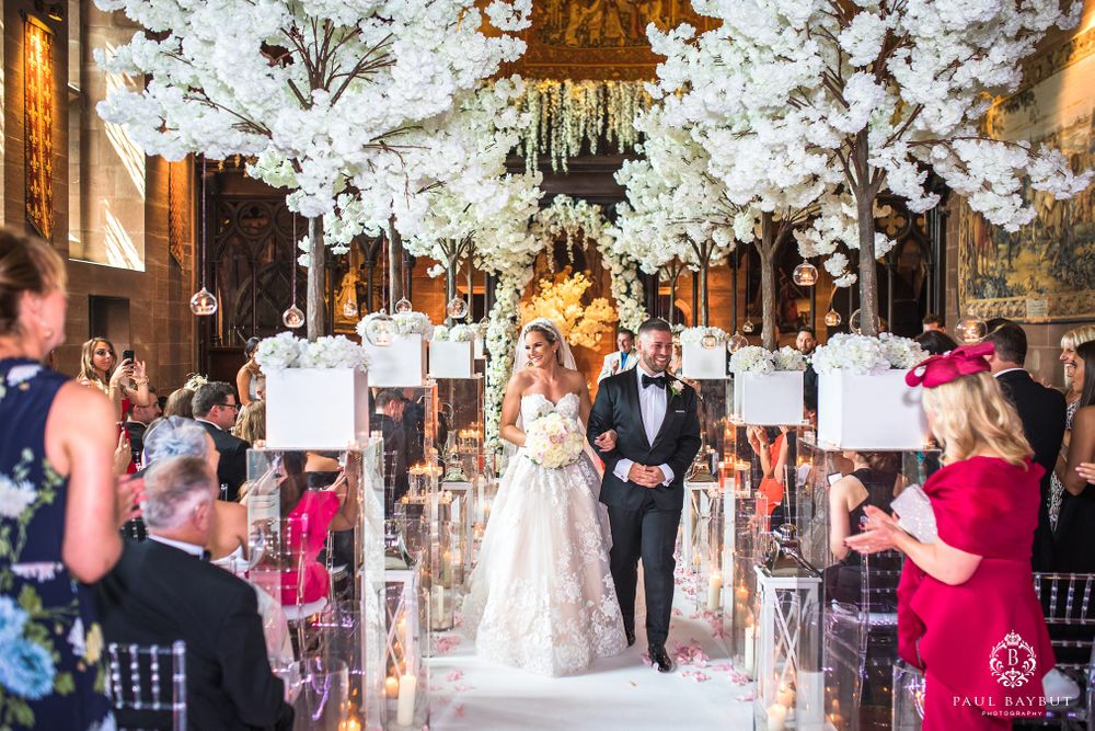Wedding ceremony exit with dramatic white floral canopy and crystal accents in rustic venue.