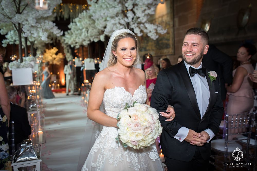 Elegant wedding couple celebrates during recessional under stunning white cherry blossom decor.