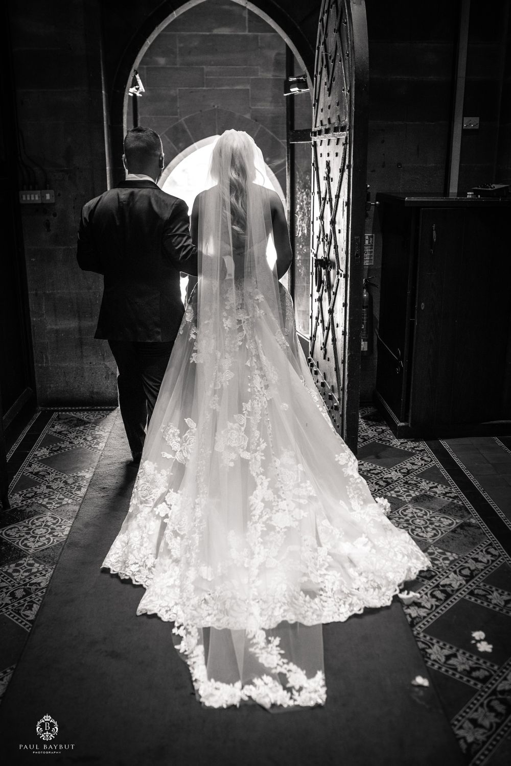 Black and white photo of wedding couple's dramatic exit through arched church doorway.