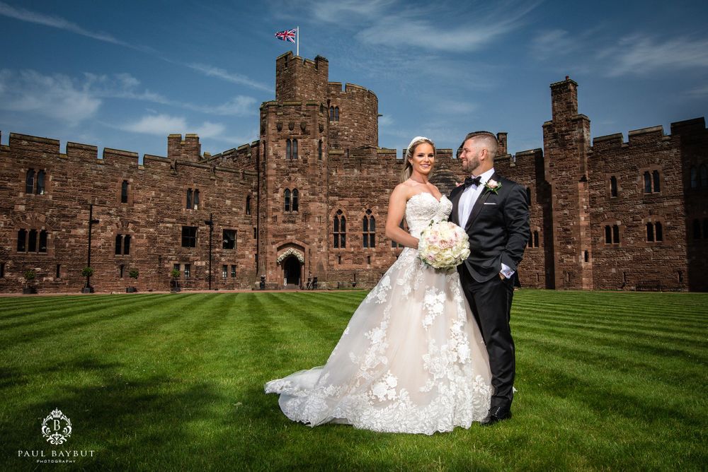 A joyful wedding moment captured in front of a medieval castle with its stone walls and towers.