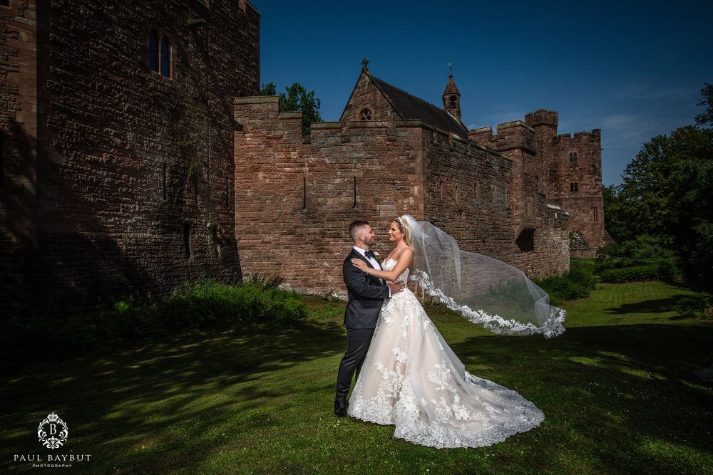 Elegant wedding portrait with flowing veil against medieval castle architecture.