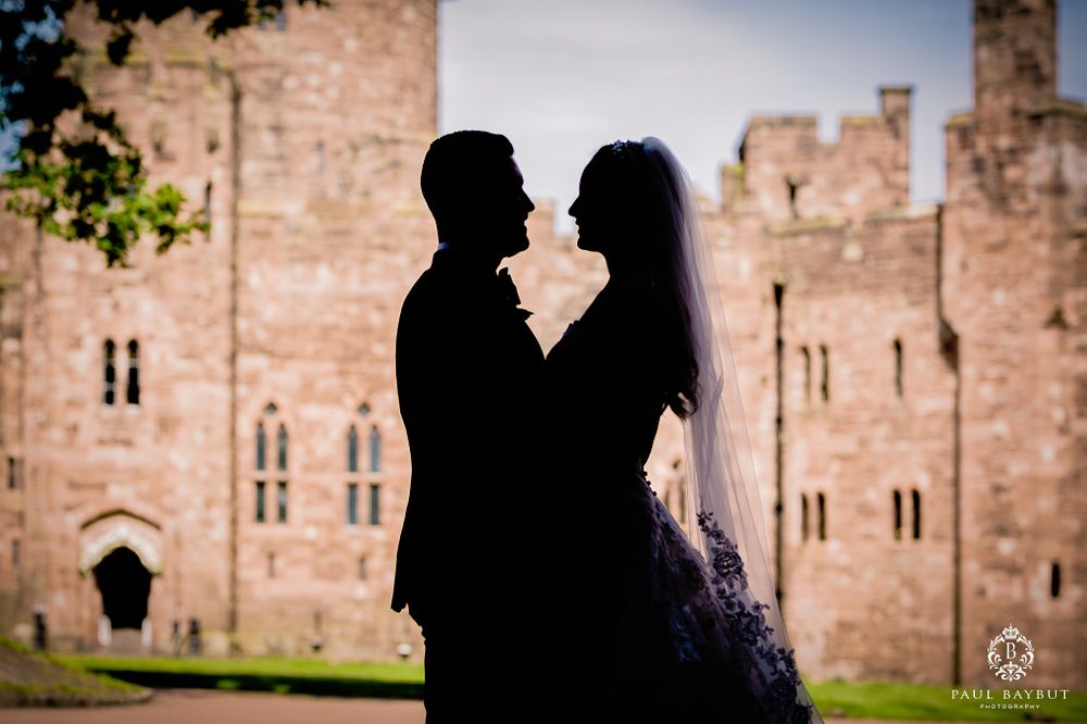 Silhouetted figures create a romantic scene against the backdrop of an ancient castle at dusk.