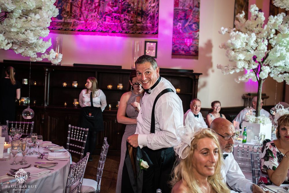 Wedding reception scene with decorative white trees and purple lighting in an elegant venue.