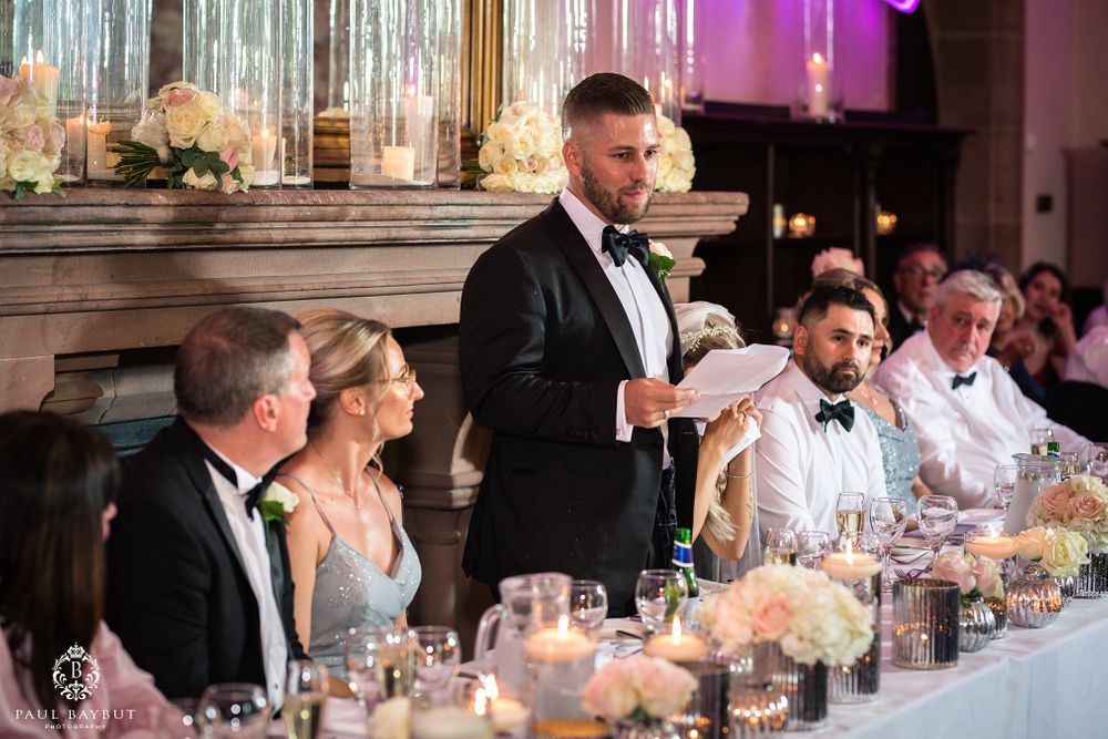 Wedding reception toast at head table with elegant floral centerpieces and pink ambient lighting.