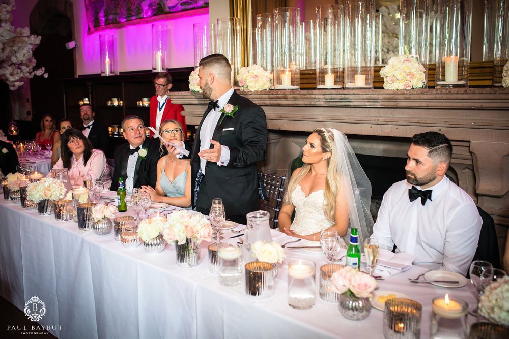 Head table speech during wedding reception with romantic candlelight and floral arrangements.