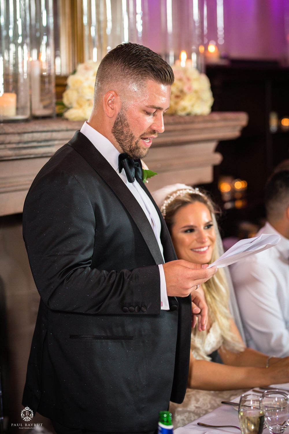 Formal speech delivery at elegant wedding reception with crystal decor and romantic lighting.