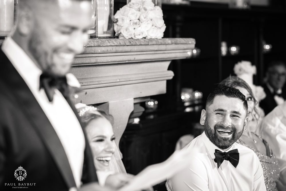 Candid reactions during wedding reception speeches with guests seated at decorated tables.