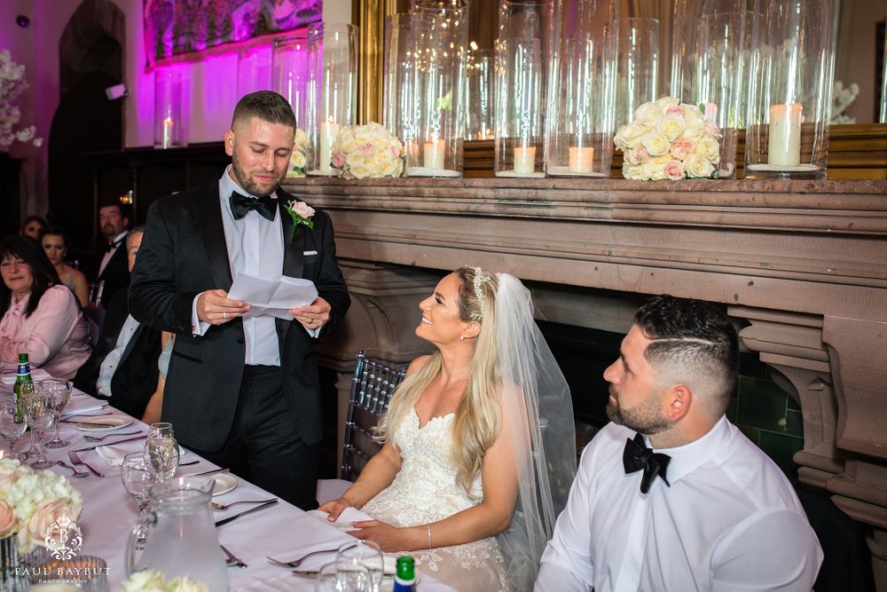 A reception speech being delivered at the head table with decorative lighting and floral arrangements.
