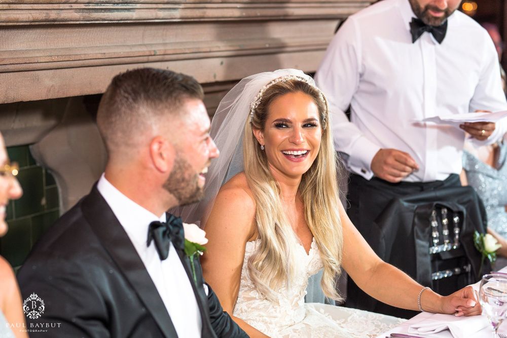 Newlyweds share a joyful moment at their reception table during wedding celebrations.