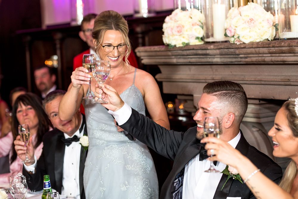 Wedding party raises glasses in celebration during reception toasts.