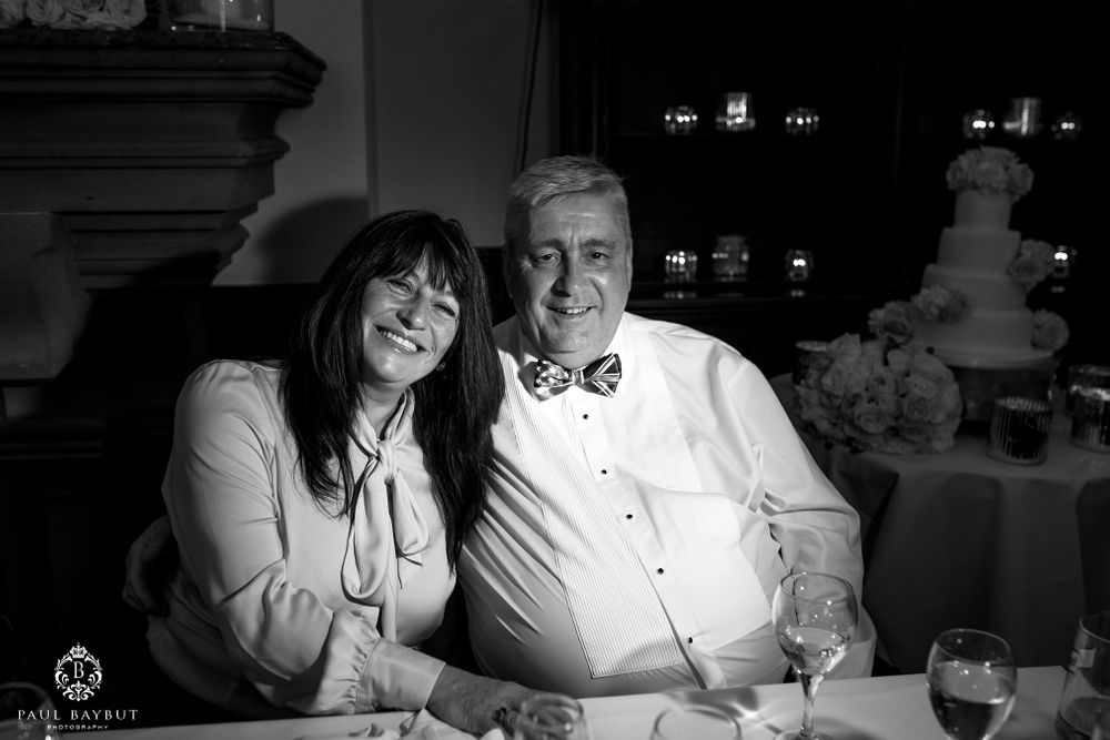 Black and white candid photo of wedding guests seated at a formal event.