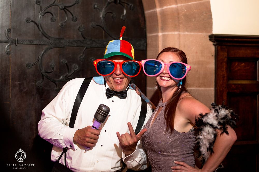 Wedding guests posing playfully with oversized sunglasses and props at a reception.