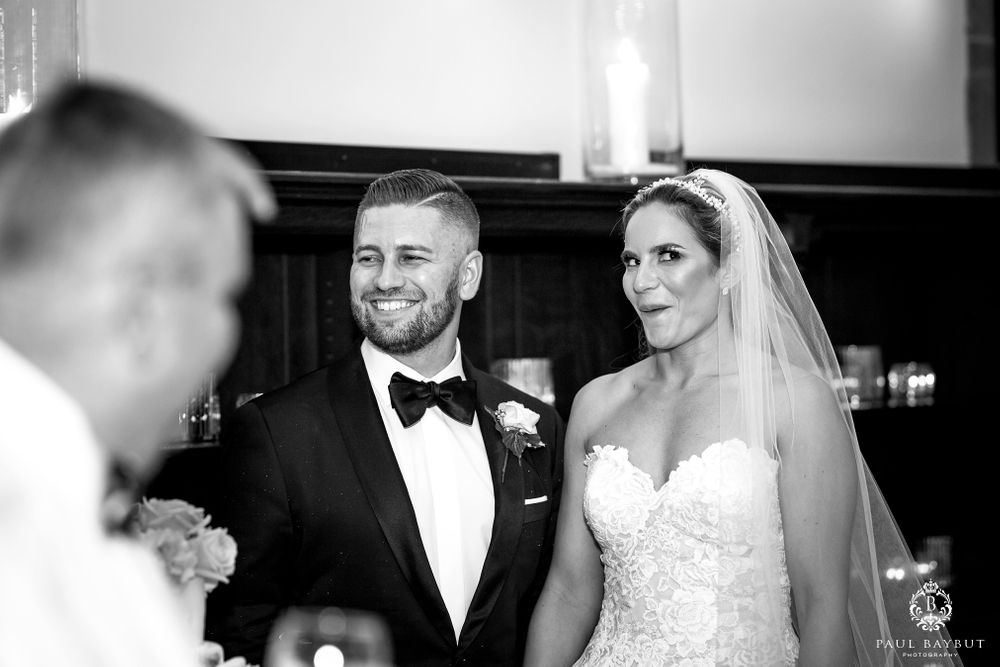Black and white wedding photo of couple sharing joyful moment at reception.