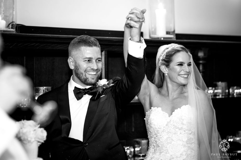 Wedding couple celebrating with raised arms in black and white photograph.