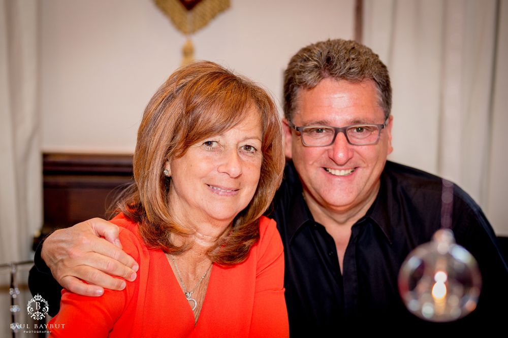 Couple in formal attire posing together at event with decorative background.
