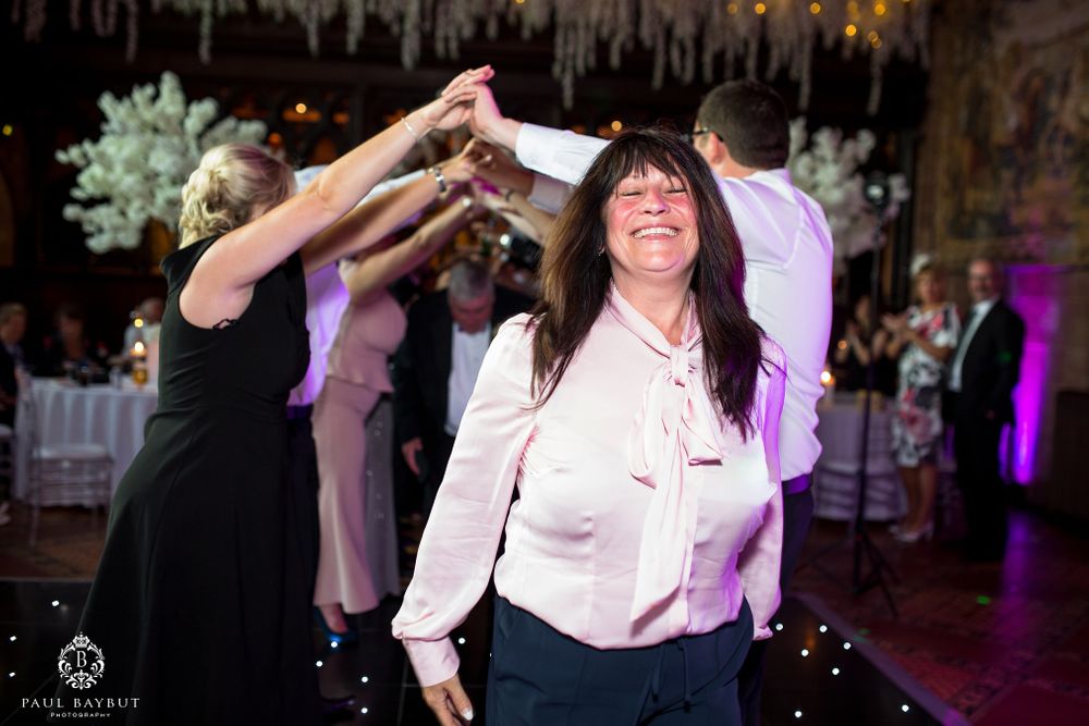 Wedding guests dance joyfully beneath decorative hanging lights at the reception.