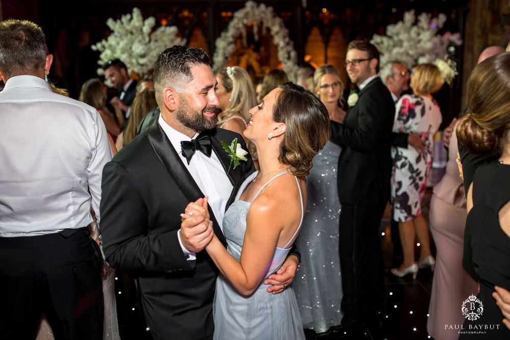 Romantic dance moment at wedding reception with elegant floral decorations in background.