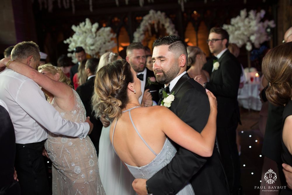 Tender dance moment at wedding reception with guests in background.