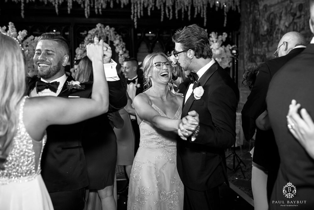 Wedding guests dance and celebrate together on the dance floor under decorative ceiling installations.