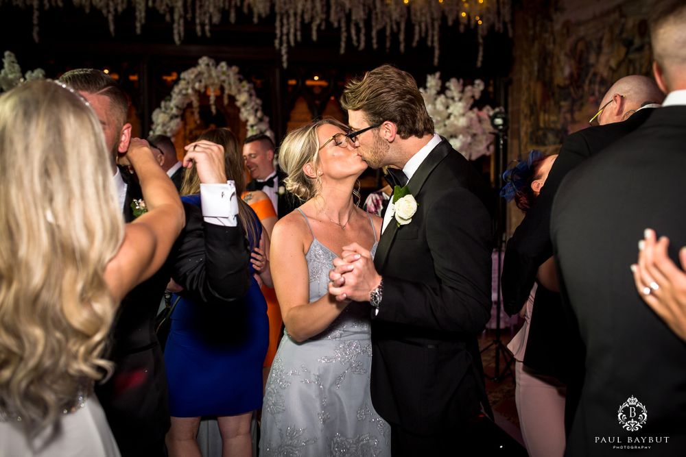 Couples dance together during a wedding reception beneath elegant hanging decor.