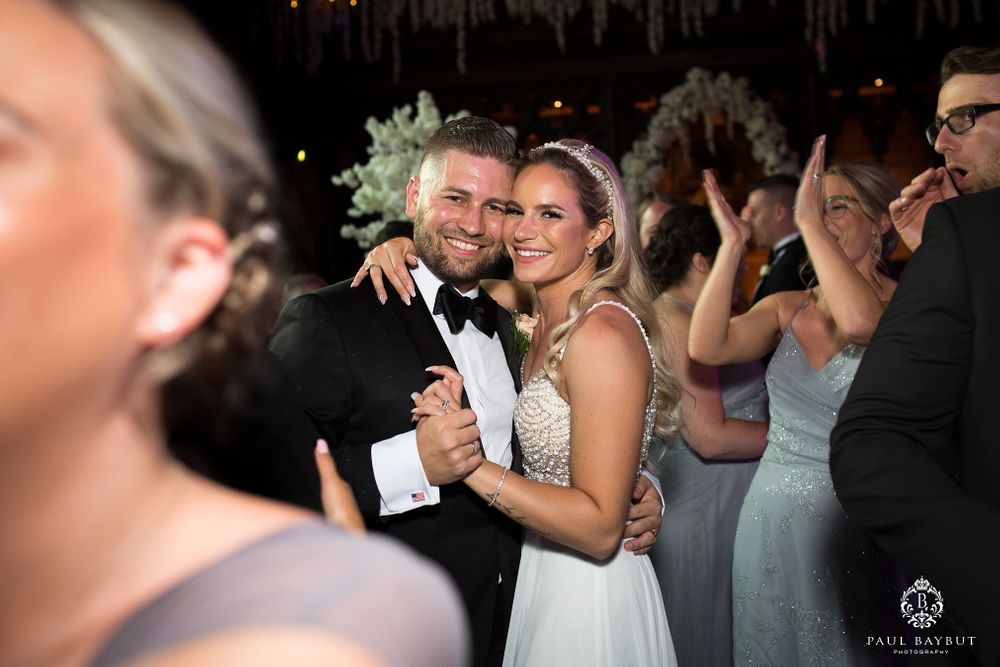 Couples dance together at an elegant wedding reception under hanging decorations.