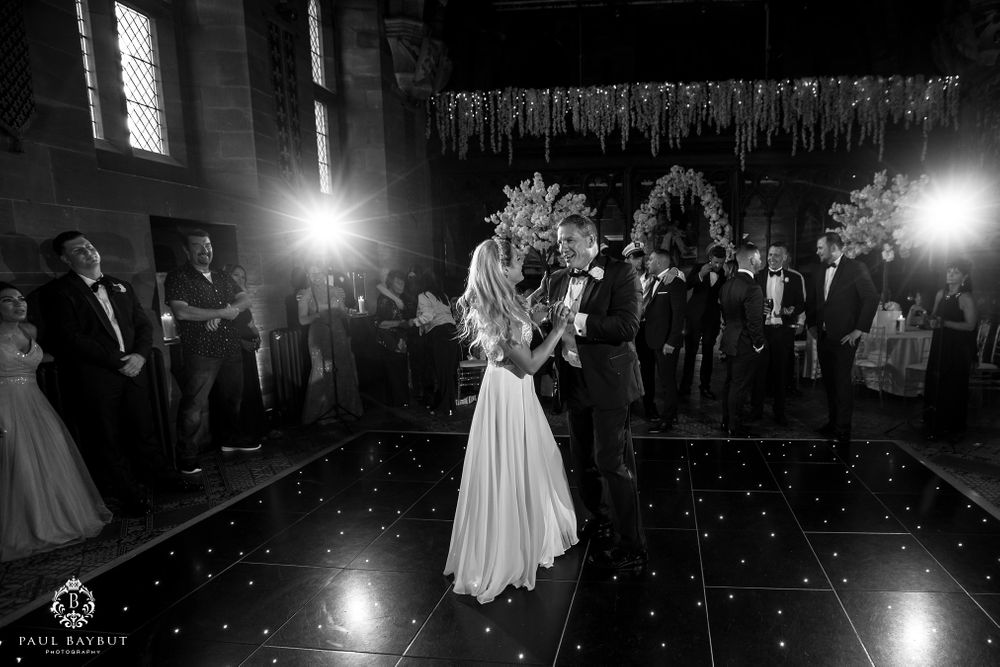A romantic wedding dance captured in monochrome on an illuminated dance floor.