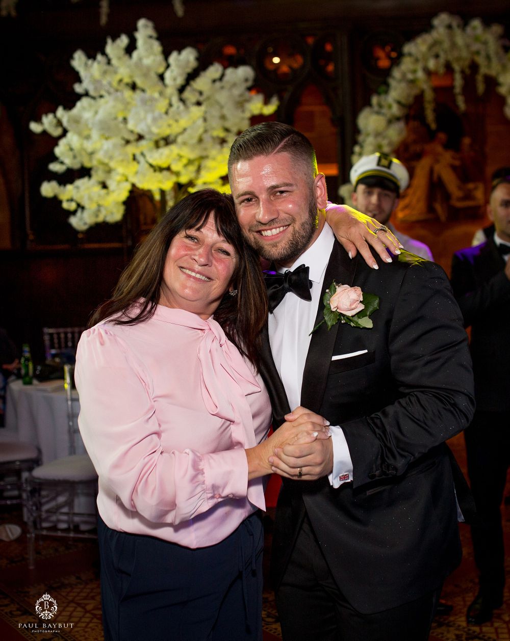A dance moment at a wedding reception featuring dancers in formal attire with pink and black colors under elegant floral decor.