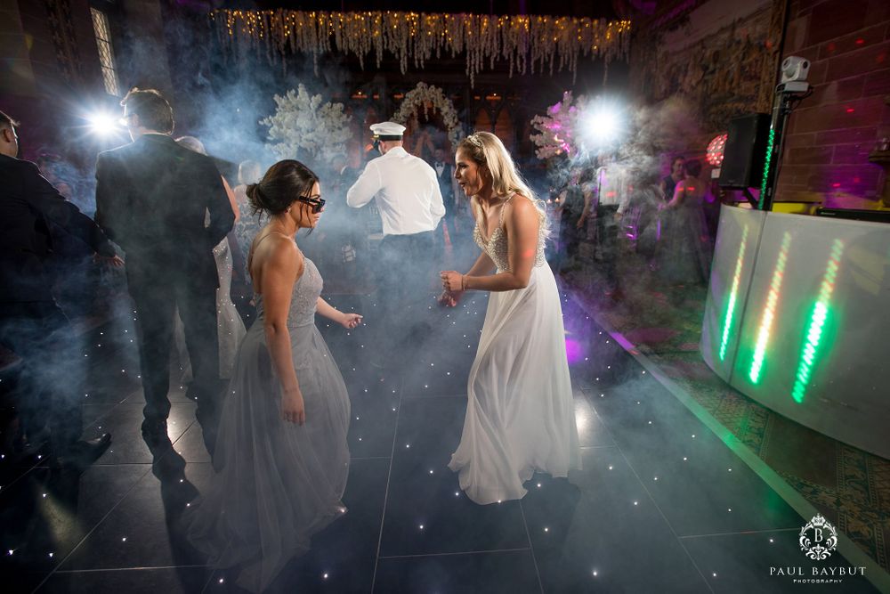 Guests dancing at wedding reception with atmospheric fog and colored lighting effects.