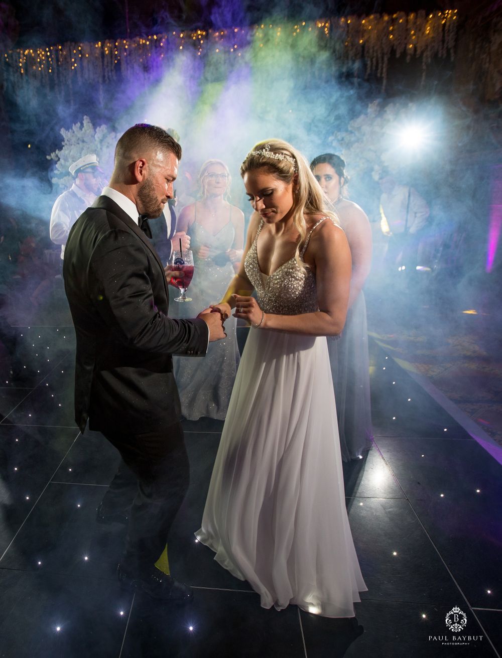 Atmospheric wedding dance moment captured with dramatic fog and colorful lighting effects.