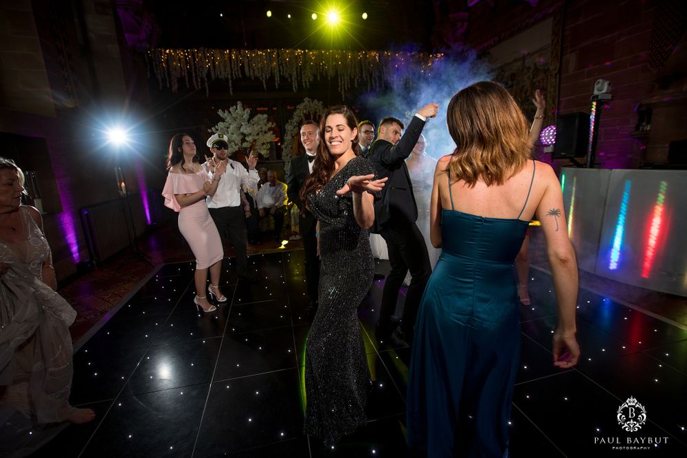 Wedding reception dance floor filled with guests enjoying the celebration under dramatic lighting.