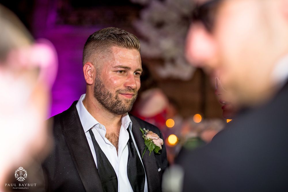 Candid reception moment in formal attire with soft purple lighting.