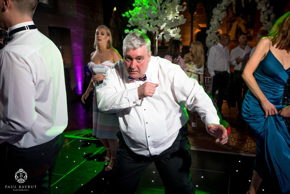 Energetic guest shows off dance moves on the wedding reception floor with green lighting.