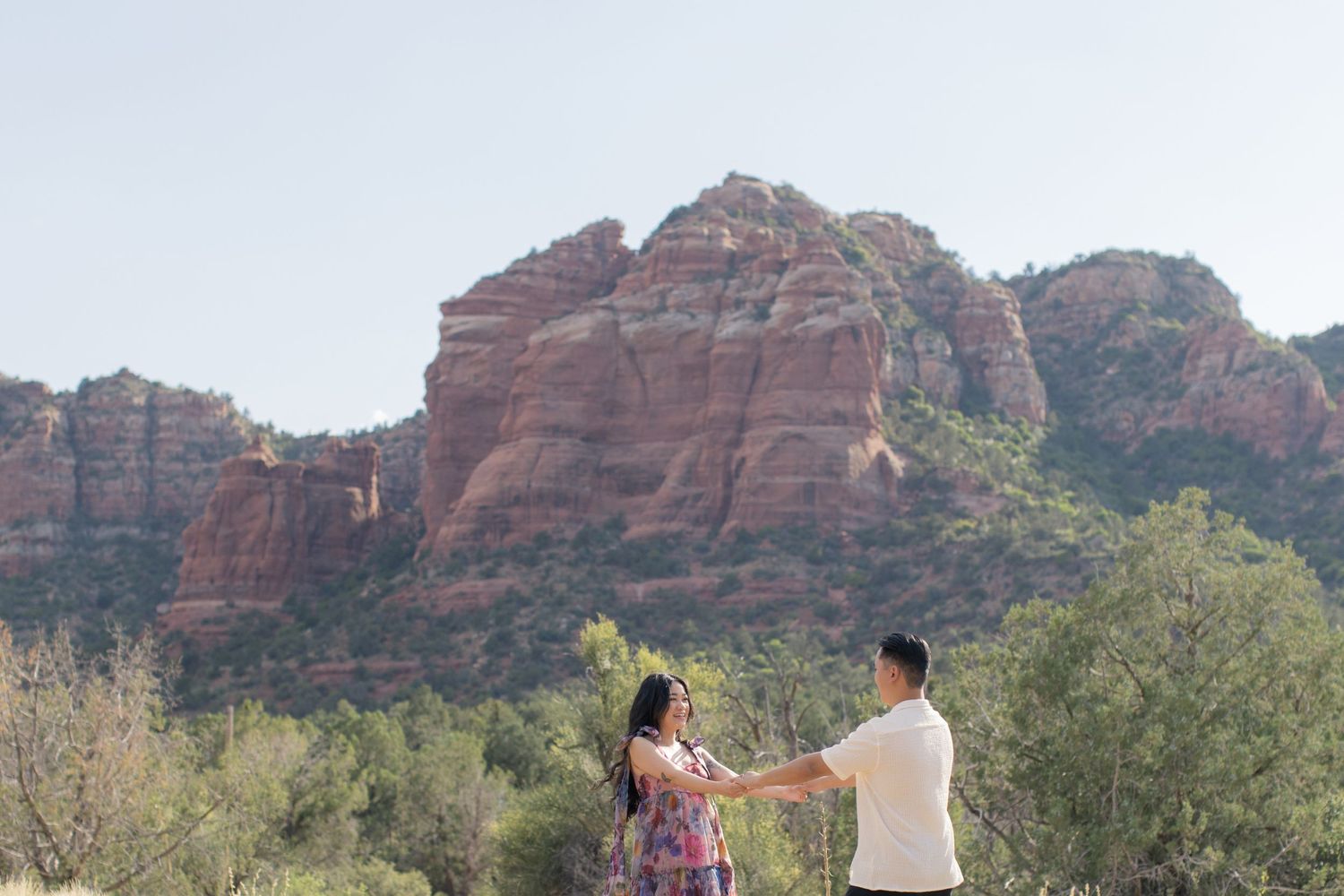 Couple holding hands against stunning red rock formations in Sedona, Arizona.