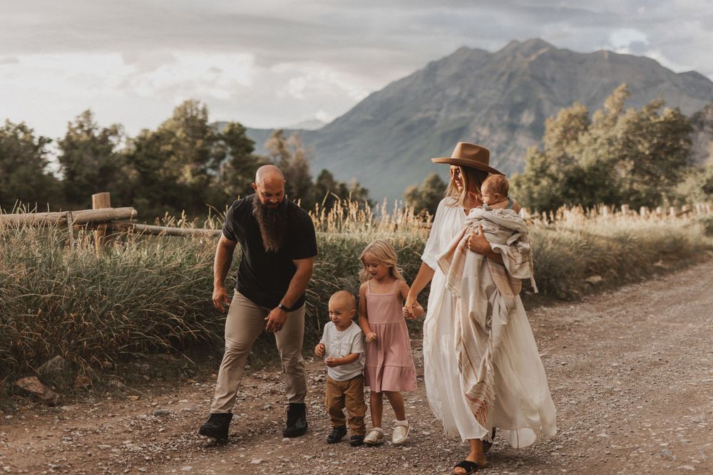Family walking together on a dirt path with majestic mountains in the distance.