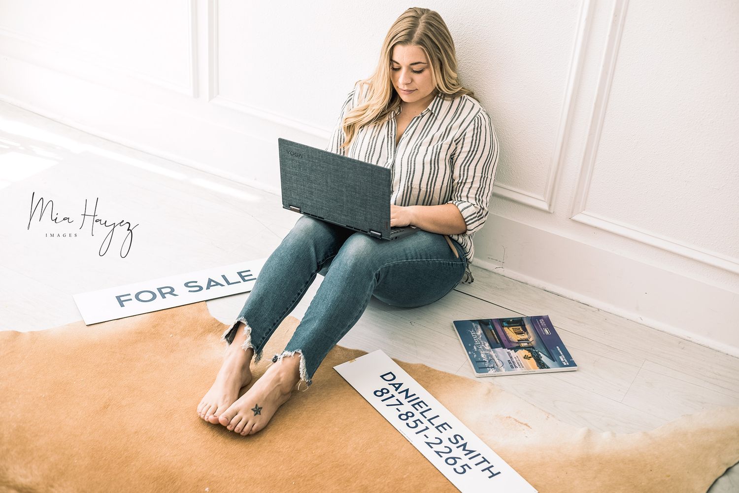 Lifestyle photoshoot showing person relaxing with magazines and for sale signs in white room.