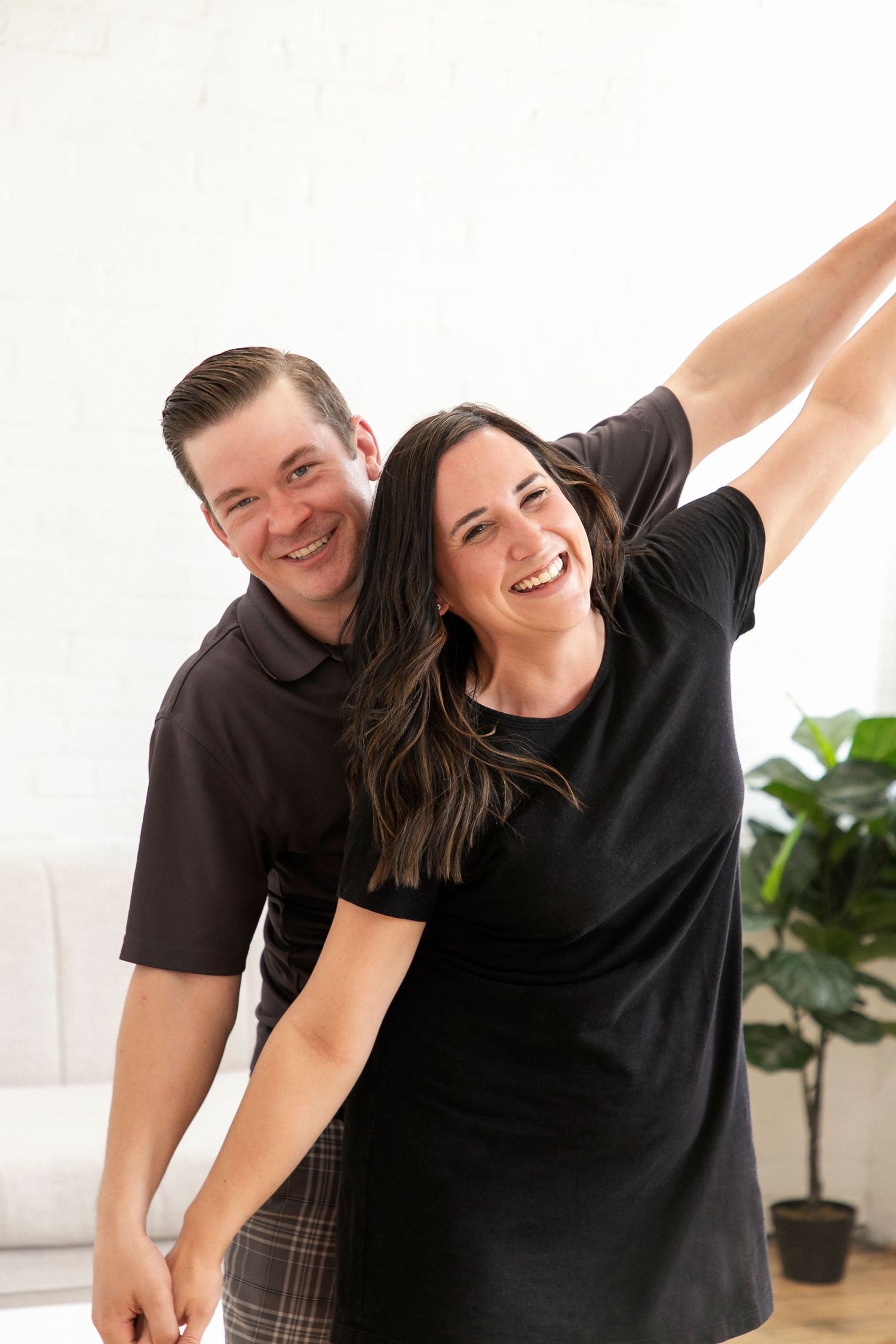 A woman with her hands reached out and her fiance behind her doing the same while they hold hands.